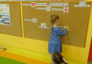 Dziewczynka przywiesza na tablicy symbol prawa do rodziny.